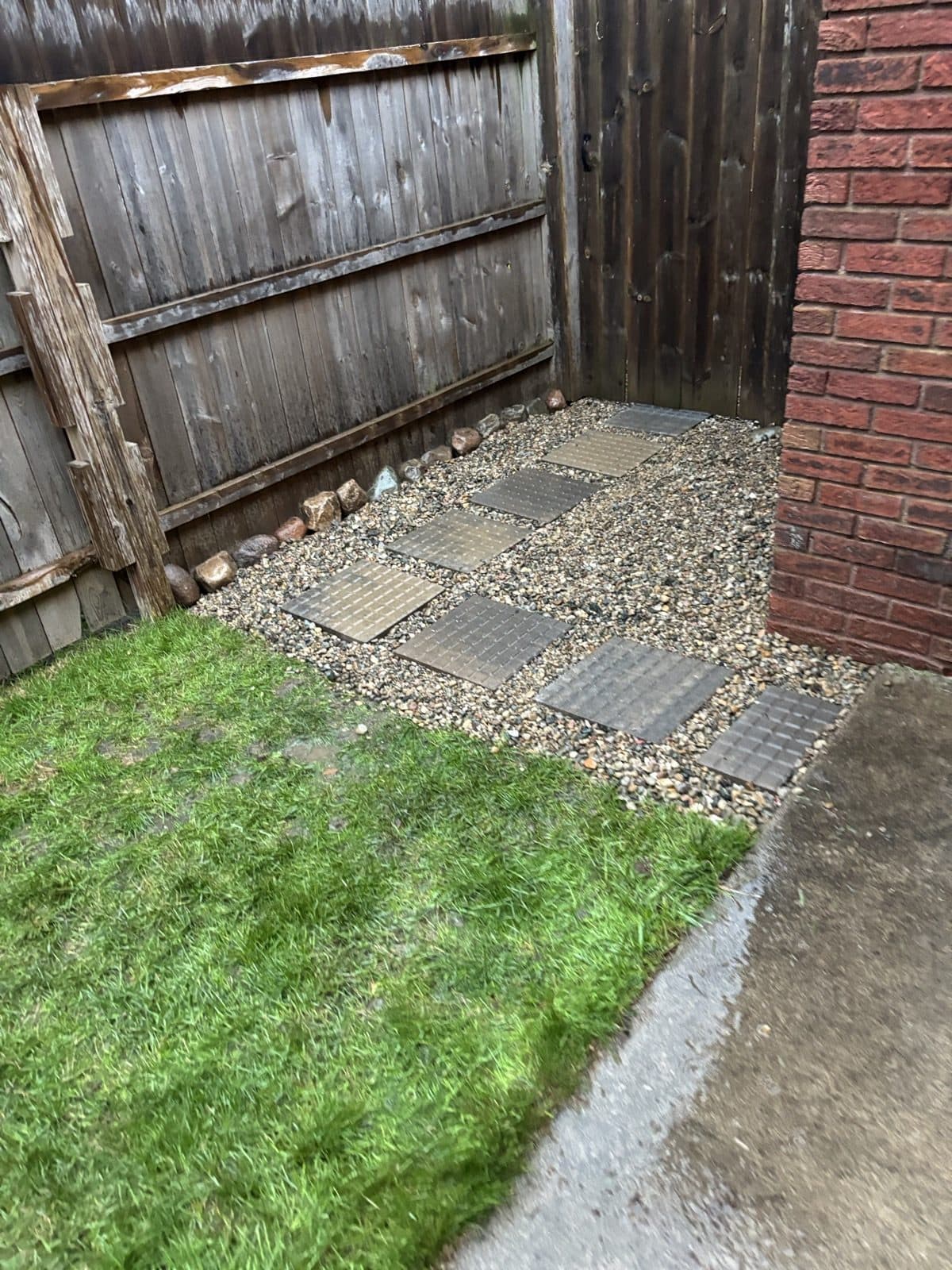 Backyard corner with a wood privacy fence, tidy lawn, and a clean gravel border strip