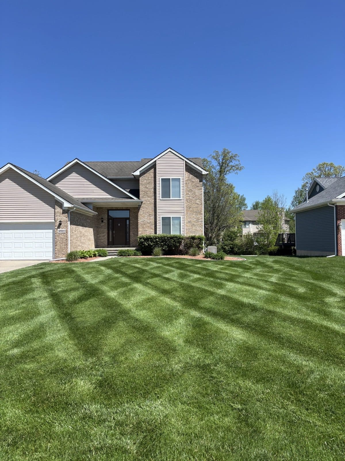 Two-story home with a freshly mowed, striped green lawn maintained by J. Molina Landscaping